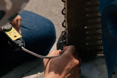A technician repairing an air conditioning unit with hand tools