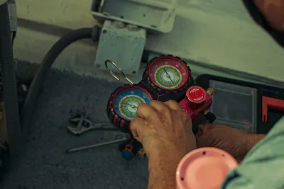 A technician adjusting a refrigerant manifold gauge during a repair
